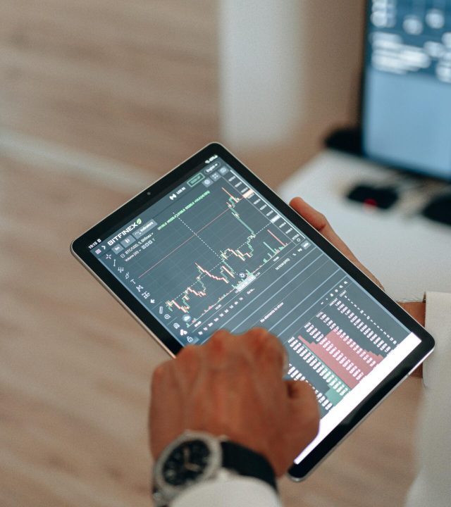 Close-up of hands using a tablet for online trading and market analysis.