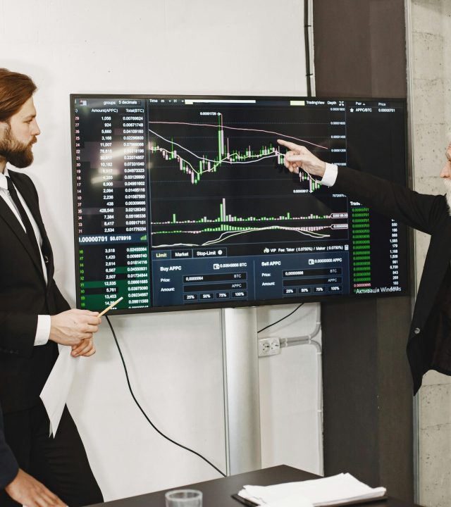 A diverse business team in a meeting analyzing stock market data on a screen.